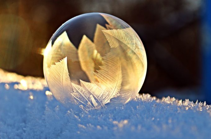 Eine Seifenblase von einem Frostmuster bedeckt wird von der Sonne angeschienen.